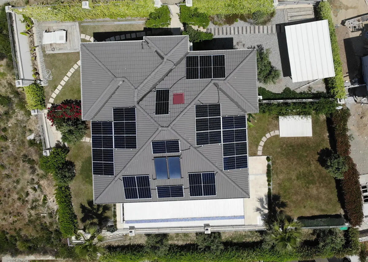 Solar panels installed on the tiled hipped roof of a villa with a pool; aerial view