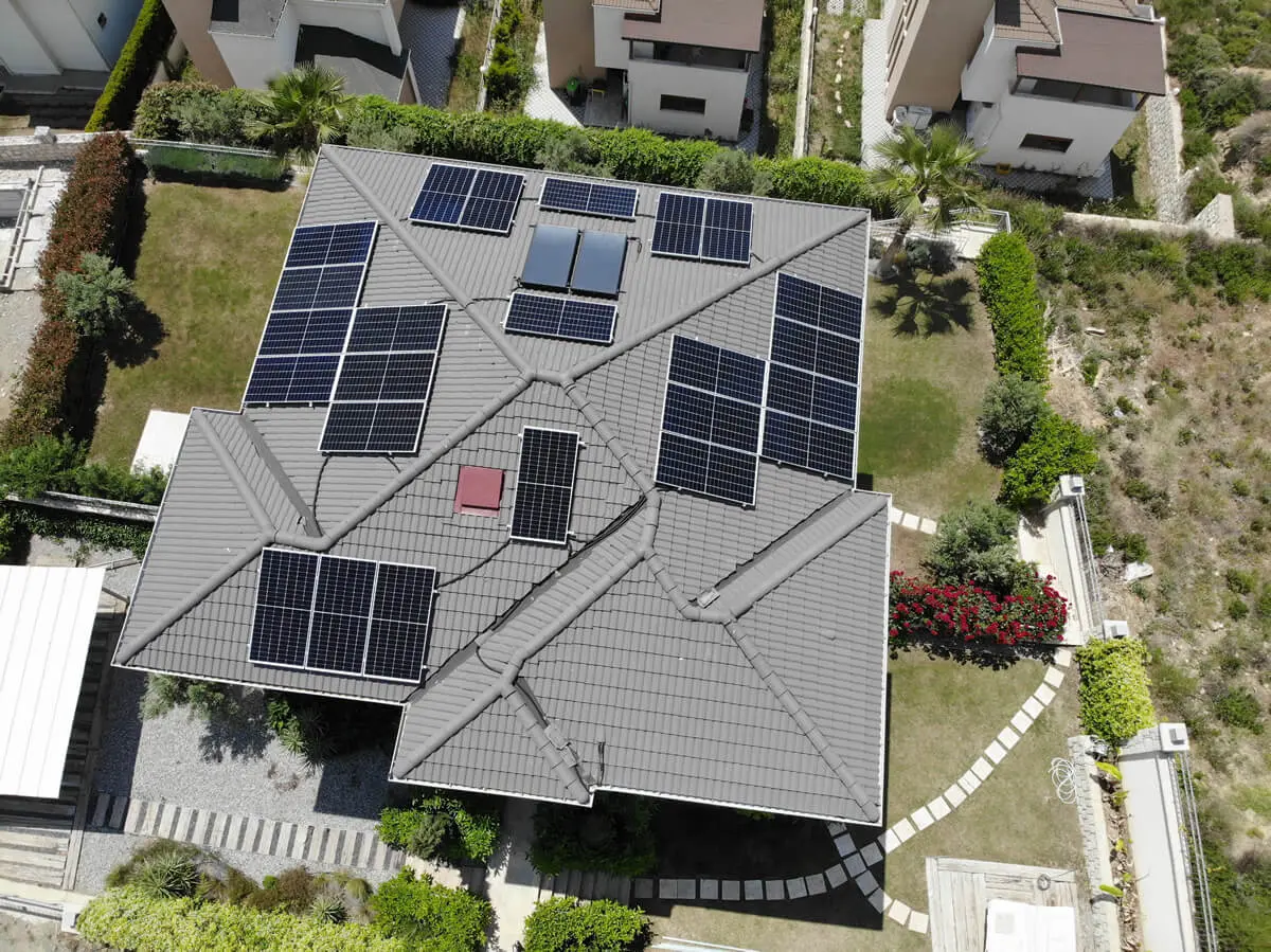 Solar panel arrays on the multi-faceted roof of a detached house; aerial view